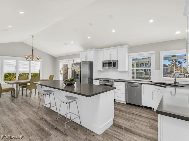 kitchen with white cabinets, appliances with stainless steel finishes, an inviting chandelier, and a wealth of natural light