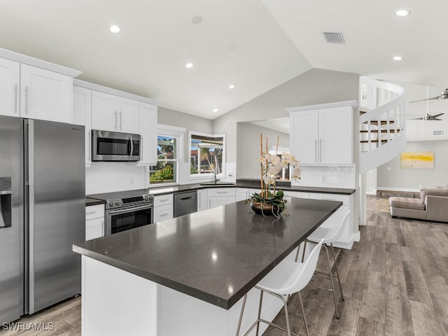 kitchen with white cabinets, backsplash, hardwood / wood-style floors, and appliances with stainless steel finishes