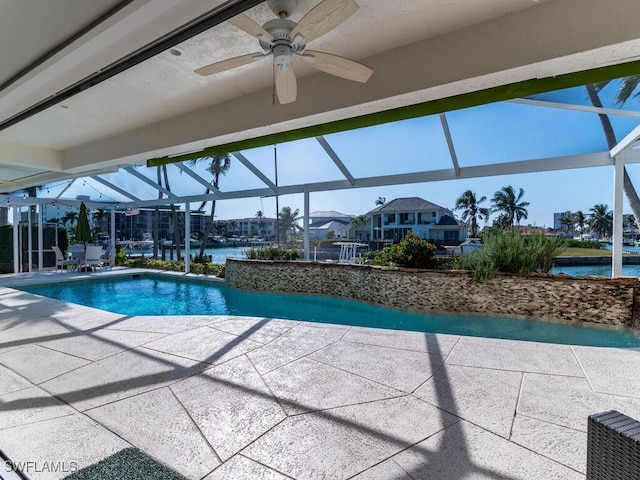 view of pool with a patio, a water view, ceiling fan, and a lanai