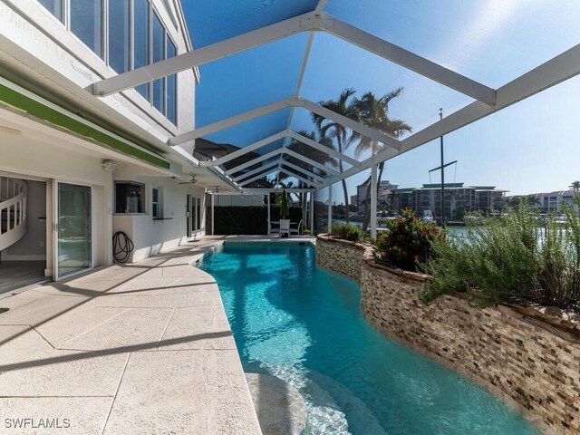 view of pool with glass enclosure and a patio