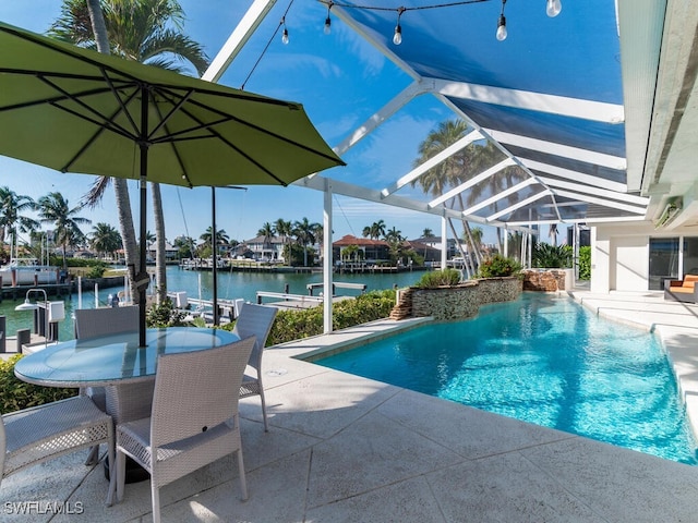 view of pool with glass enclosure, a patio area, and a water view