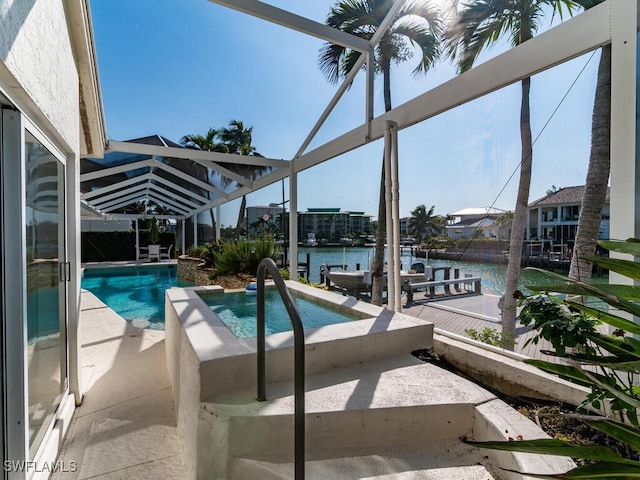 view of pool featuring glass enclosure, a patio area, a water view, and a hot tub