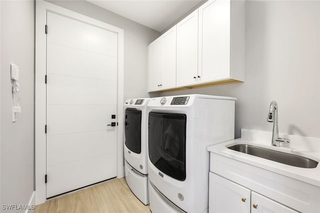 washroom featuring light wood-type flooring, cabinets, independent washer and dryer, and sink