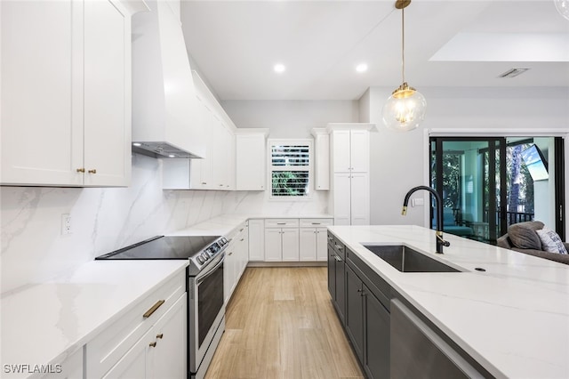 kitchen featuring white cabinetry, custom exhaust hood, stainless steel electric stove, hanging light fixtures, and sink