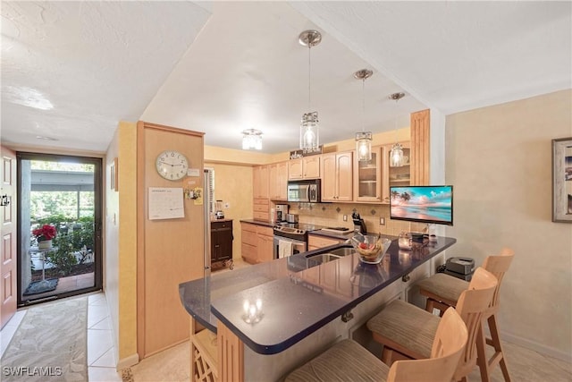 kitchen featuring kitchen peninsula, appliances with stainless steel finishes, a breakfast bar area, and light tile patterned flooring