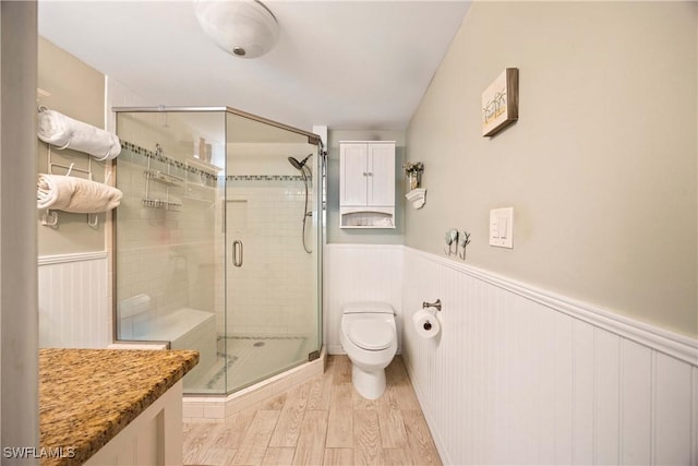 bathroom with hardwood / wood-style floors, an enclosed shower, and toilet