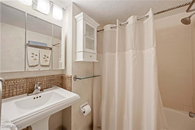 bathroom featuring tasteful backsplash, sink, shower / bathtub combination with curtain, and a textured ceiling