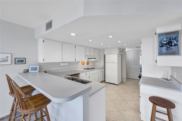 kitchen featuring a kitchen bar, white appliances, and kitchen peninsula