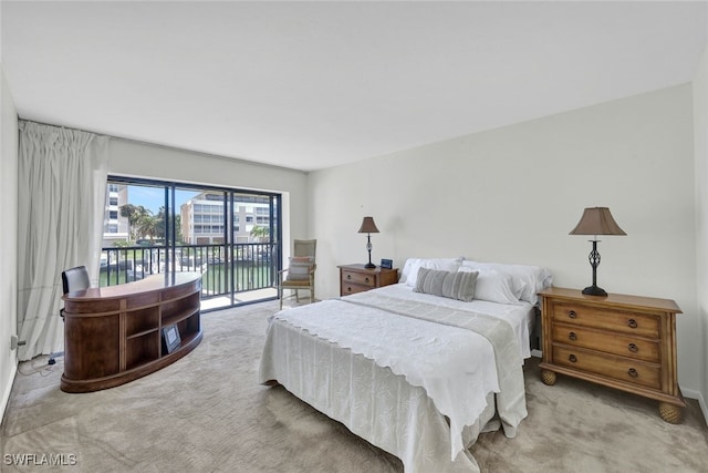 bedroom with a water view, light colored carpet, and access to outside