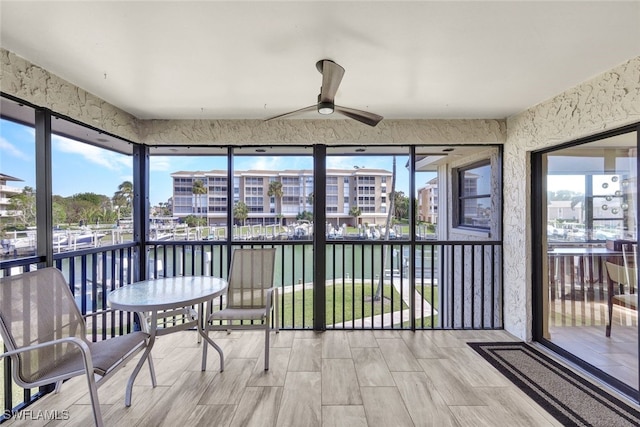 sunroom / solarium featuring ceiling fan and a water view