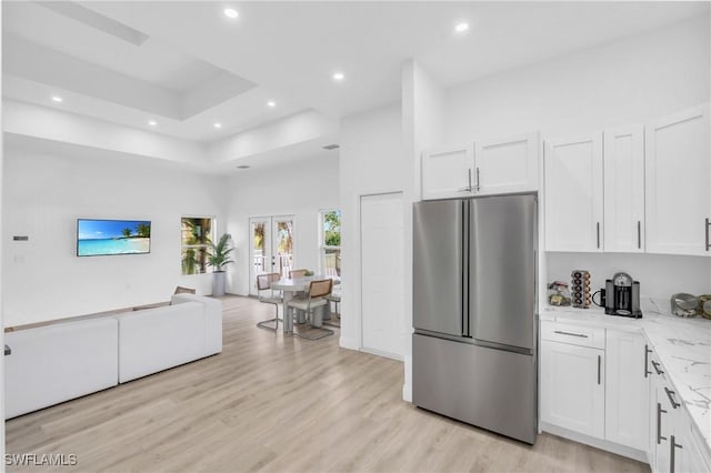 kitchen featuring stainless steel refrigerator, white cabinets, french doors, and light stone counters