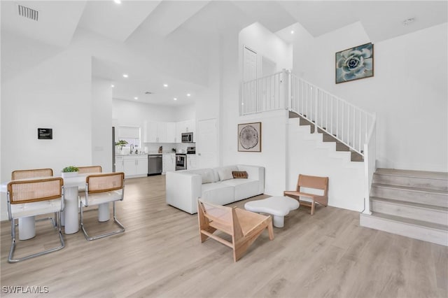 living room featuring a towering ceiling and light hardwood / wood-style flooring