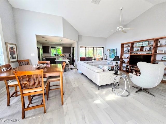 living room featuring ceiling fan, high vaulted ceiling, and light wood-type flooring