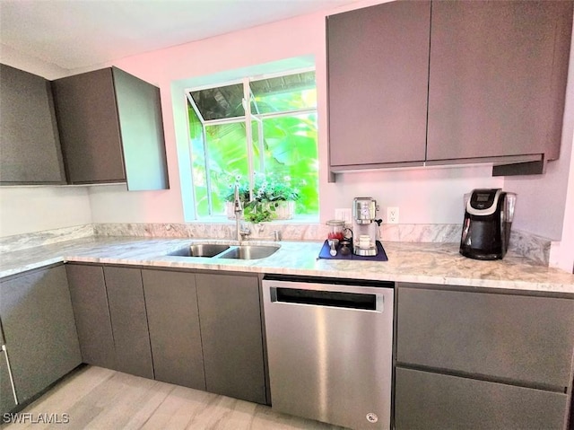 kitchen featuring light stone counters, stainless steel dishwasher, light hardwood / wood-style floors, and sink