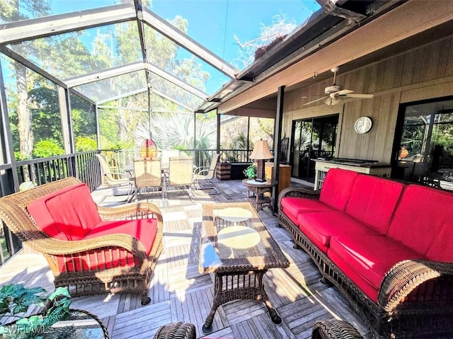 view of patio featuring a deck, outdoor lounge area, ceiling fan, and glass enclosure