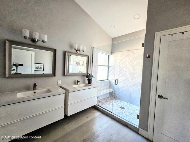 bathroom featuring hardwood / wood-style floors, vanity, vaulted ceiling, and walk in shower