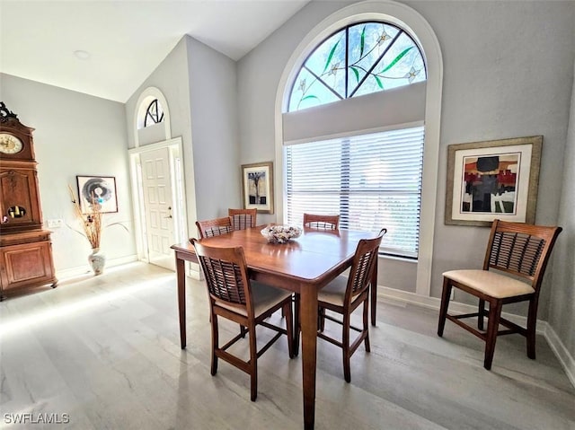 dining room with plenty of natural light, high vaulted ceiling, and light wood-type flooring