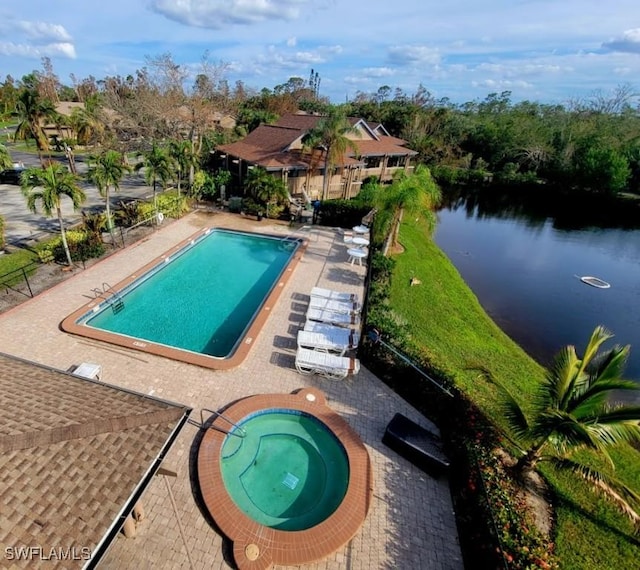 view of pool with a water view, a hot tub, and a patio area