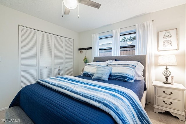 carpeted bedroom with ceiling fan, a textured ceiling, and a closet