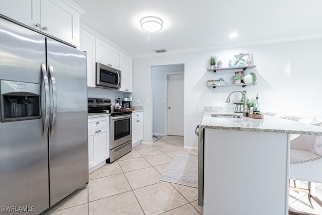 kitchen featuring light stone countertops, a kitchen breakfast bar, stainless steel appliances, sink, and white cabinetry