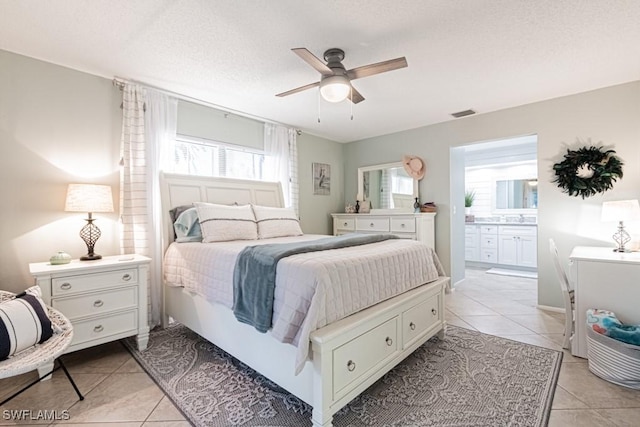 bedroom with ceiling fan, light tile patterned floors, ensuite bathroom, and a textured ceiling