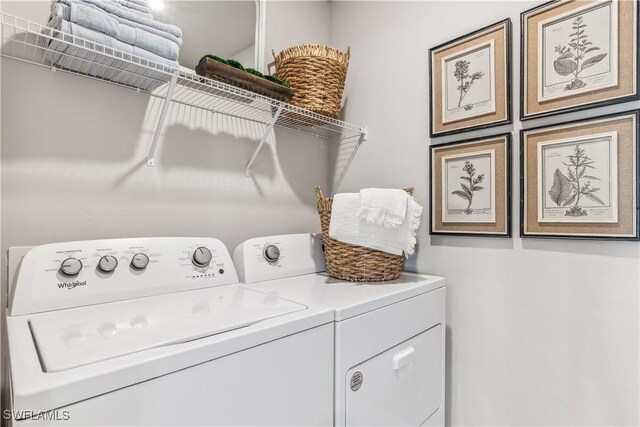 clothes washing area featuring washing machine and clothes dryer and cabinets