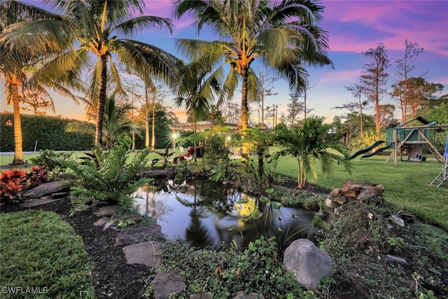 yard at dusk featuring a playground