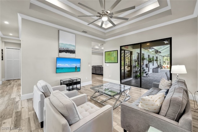 living room featuring a tray ceiling, ceiling fan, crown molding, and light hardwood / wood-style floors