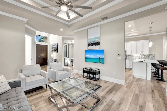 living room featuring a tray ceiling, light hardwood / wood-style flooring, ceiling fan, and ornamental molding