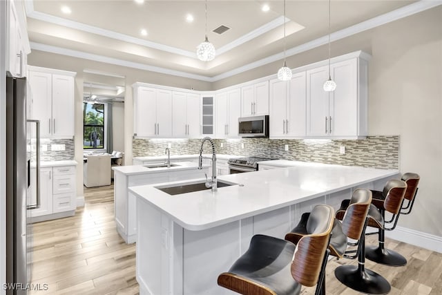 kitchen with pendant lighting, a kitchen breakfast bar, sink, white cabinetry, and stainless steel appliances