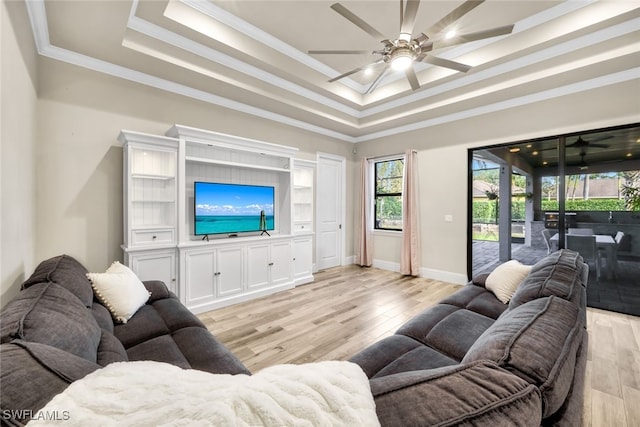 living room featuring ceiling fan, ornamental molding, and a tray ceiling