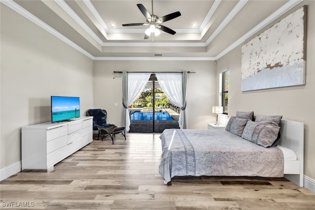 bedroom with access to outside, light hardwood / wood-style flooring, ceiling fan, and a tray ceiling