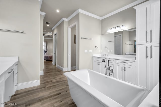 bathroom featuring a washtub, wood-type flooring, vanity, and ornamental molding