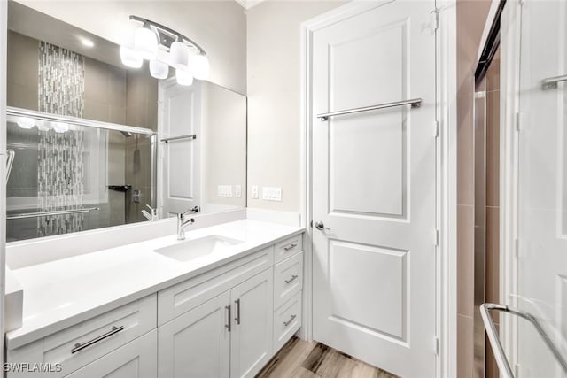 bathroom with hardwood / wood-style flooring, vanity, and an enclosed shower