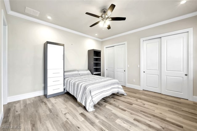 bedroom with ornamental molding, light hardwood / wood-style flooring, ceiling fan, and multiple closets