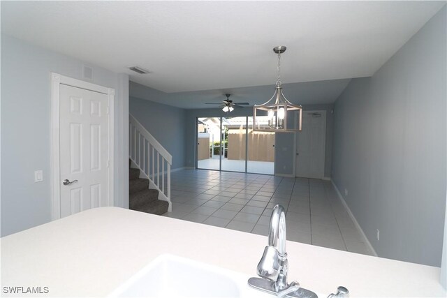 tiled dining space featuring ceiling fan with notable chandelier