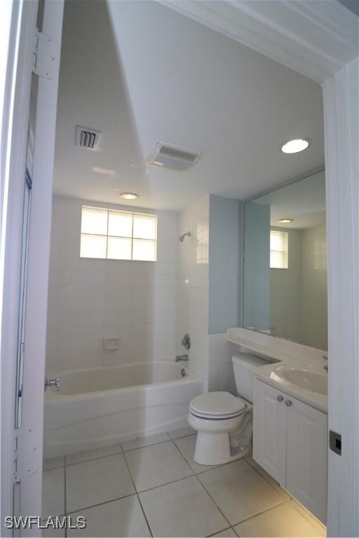 full bathroom featuring tile patterned flooring, vanity, tiled shower / bath combo, and toilet