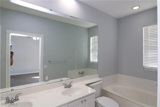 bathroom featuring vanity, a bathtub, and toilet