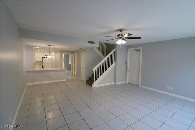 unfurnished living room with light tile patterned floors, ceiling fan with notable chandelier, and sink