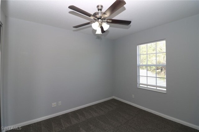 spare room with ceiling fan and dark carpet