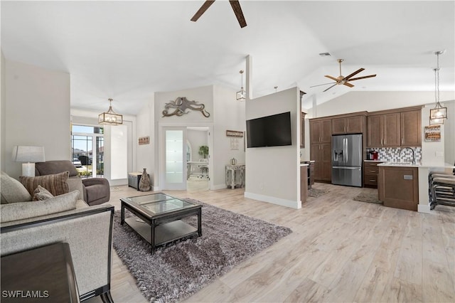 living room featuring ceiling fan, light wood-type flooring, sink, and lofted ceiling