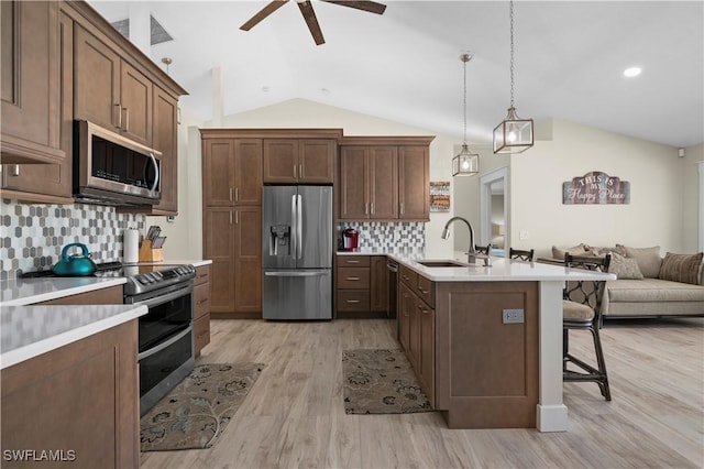 kitchen featuring tasteful backsplash, stainless steel appliances, vaulted ceiling, sink, and pendant lighting