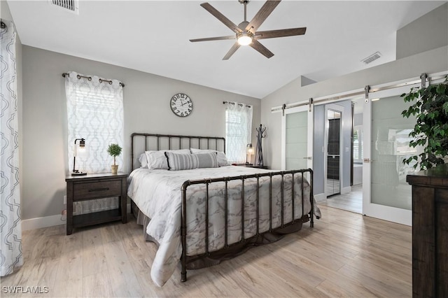 bedroom featuring a barn door, ceiling fan, light hardwood / wood-style flooring, and lofted ceiling