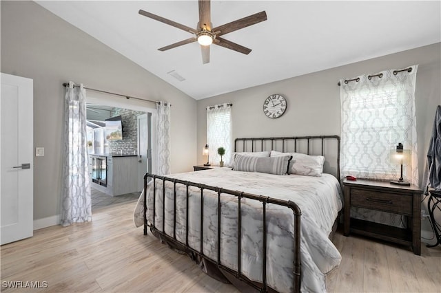 bedroom with multiple windows, ceiling fan, vaulted ceiling, and light wood-type flooring