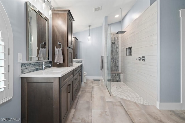 bathroom featuring vanity, toilet, and a shower with door