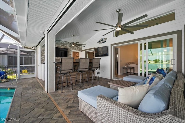 view of patio with a lanai, ceiling fan, a bar, and an outdoor hangout area