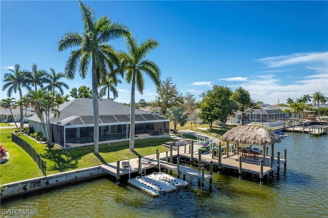 view of dock with glass enclosure, a yard, and a water view