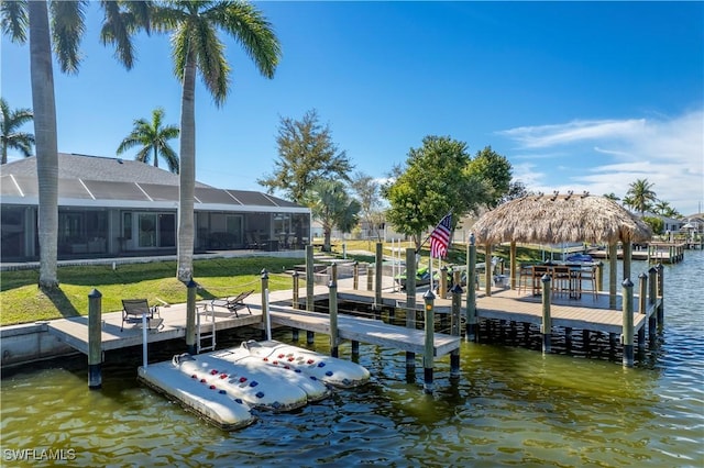 dock area with a water view, a lanai, and a lawn