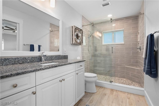 bathroom featuring ceiling fan, toilet, vanity, a shower with shower door, and hardwood / wood-style flooring