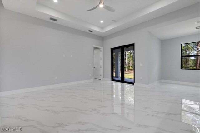 unfurnished room with ceiling fan and a tray ceiling